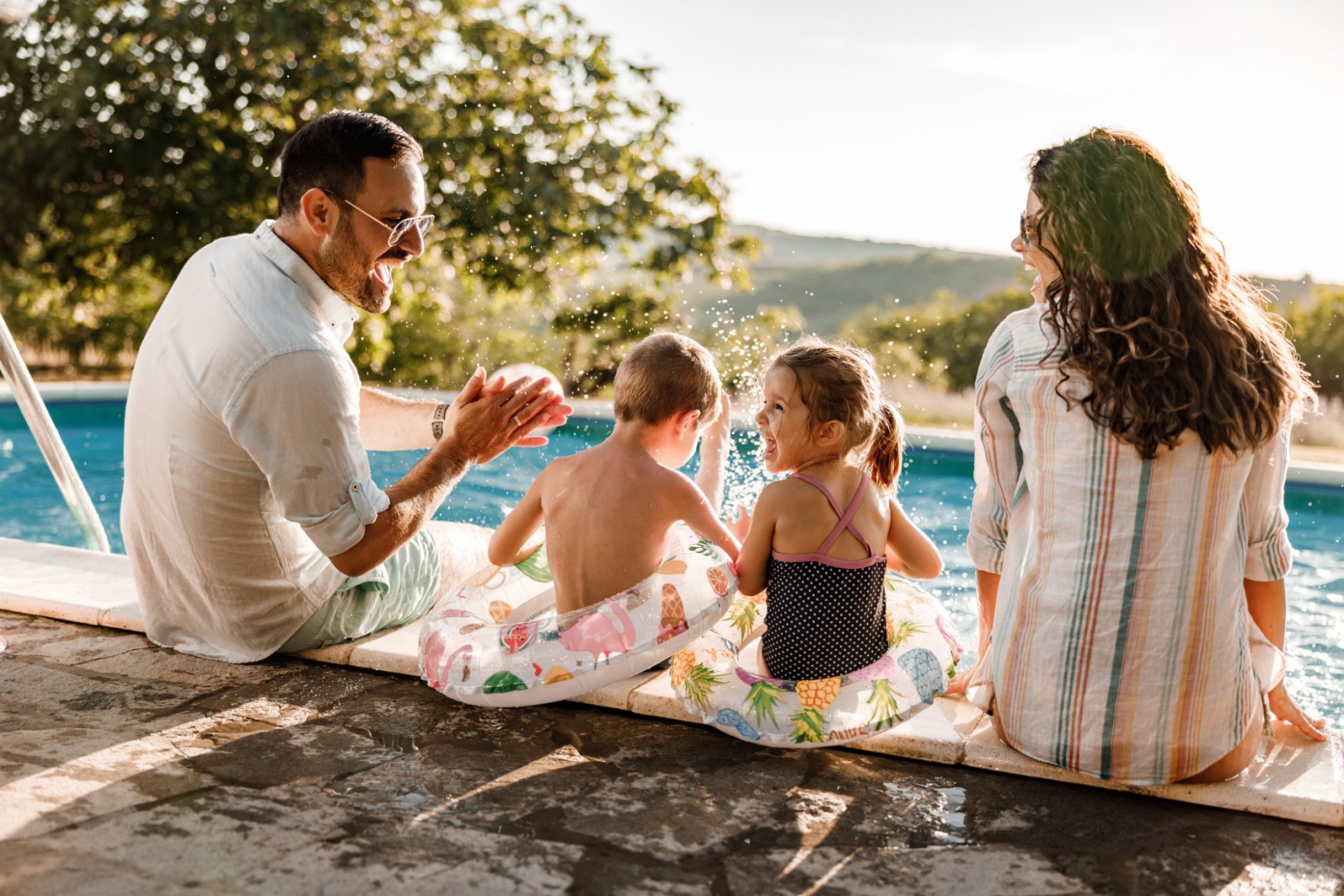 Familie während ihren Ferien am Schwimmbadrand