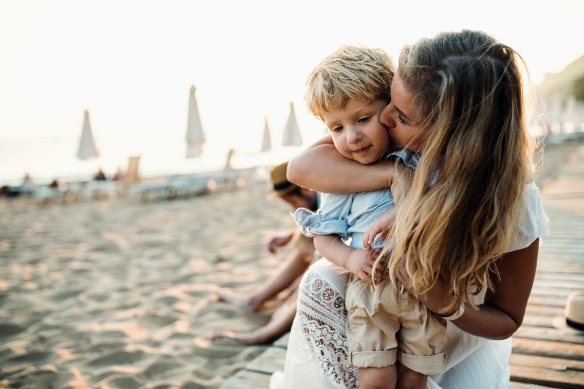 Femme prenant son enfant dans ses bras à la plage.