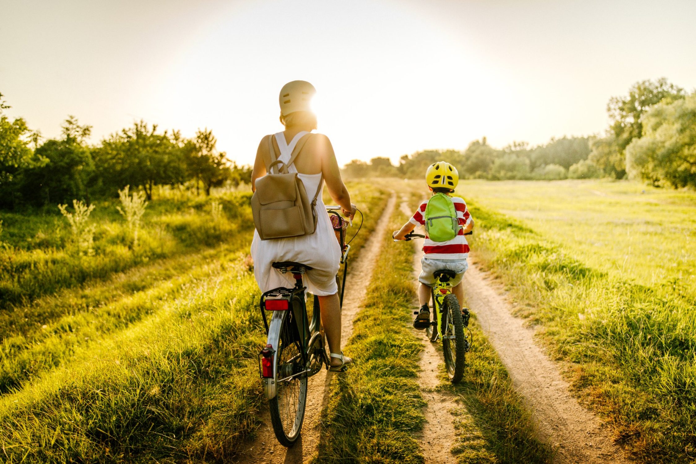 Une femme et un enfant se dirigent vers le soleil sur un chemin de terre.